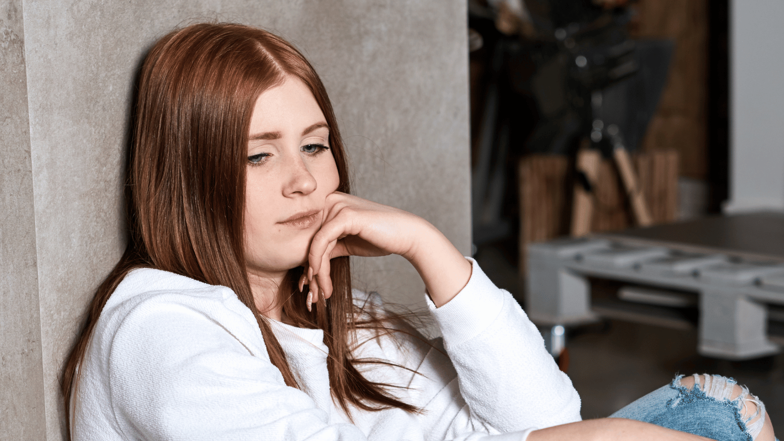 Young girl sitting against a wall