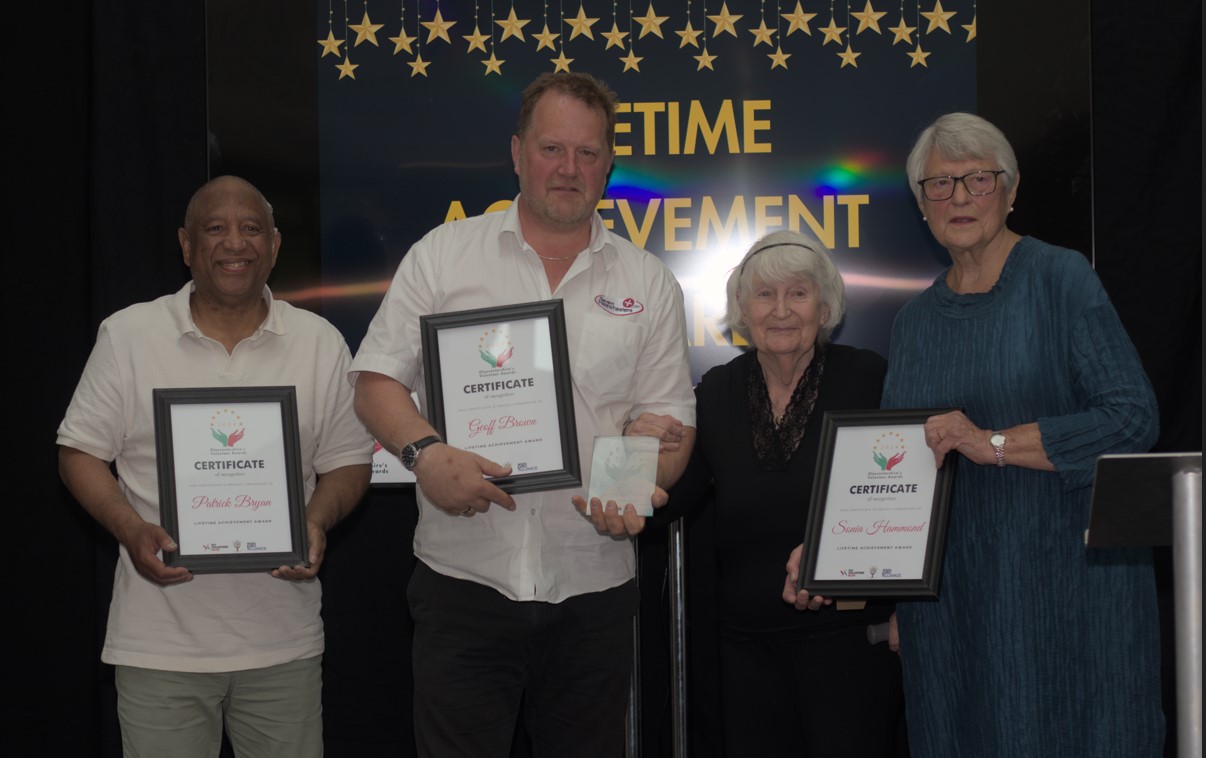 Award winners and finalists holding certificates and award on stage