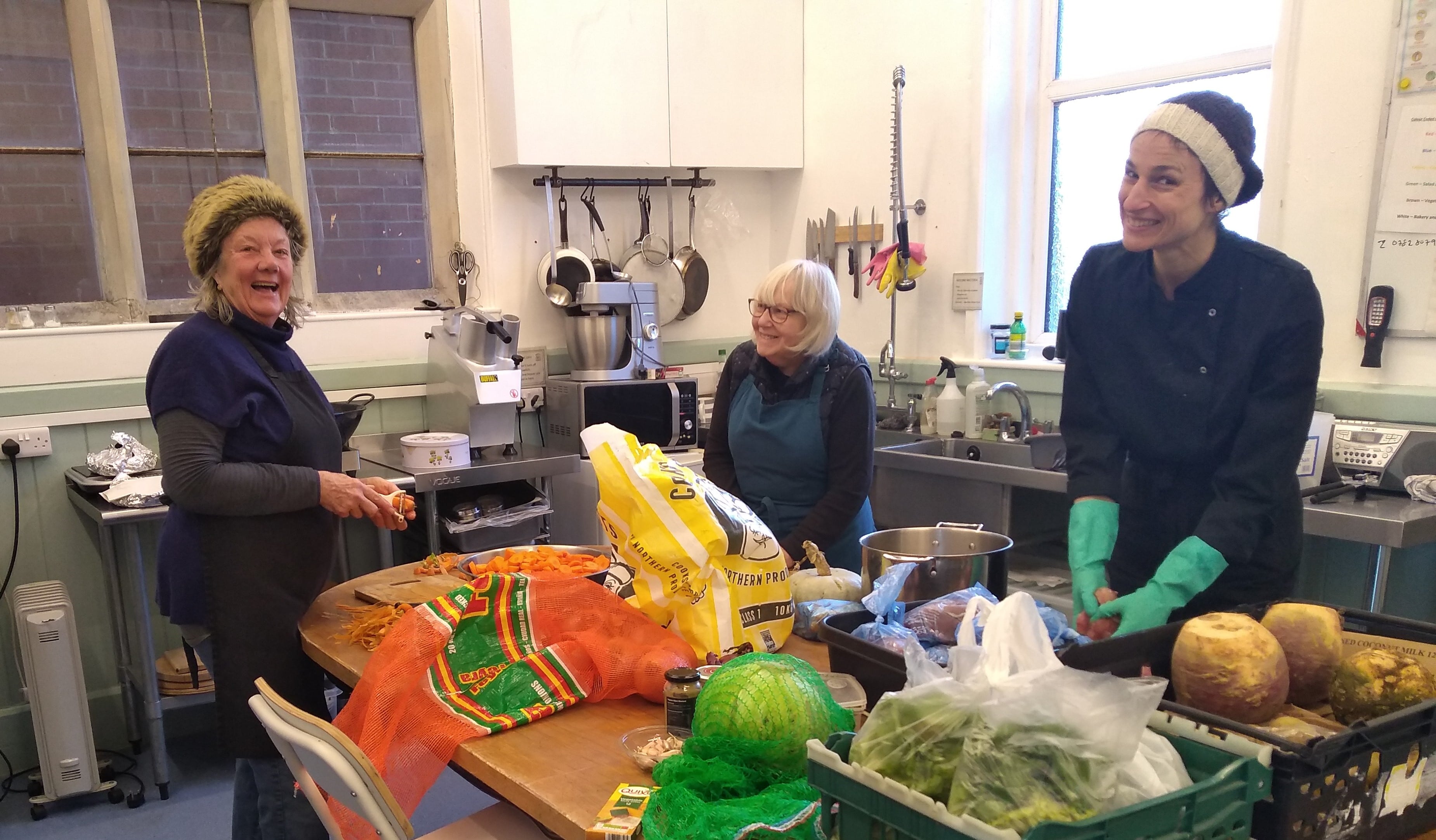 Three volunteers in kitchen prepping a meal